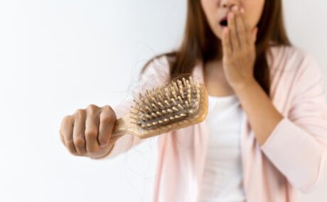 O femeie care se confruntă cu căderea părului după naștere și are multe fire rupte în peria de păr