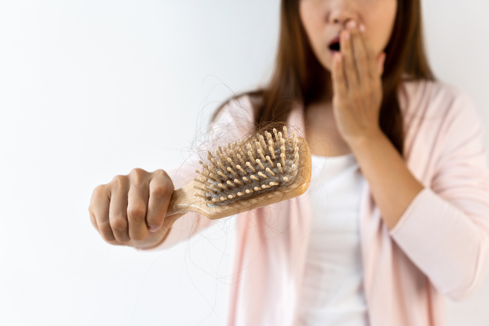 O femeie care se confruntă cu căderea părului după naștere și are multe fire rupte în peria de păr