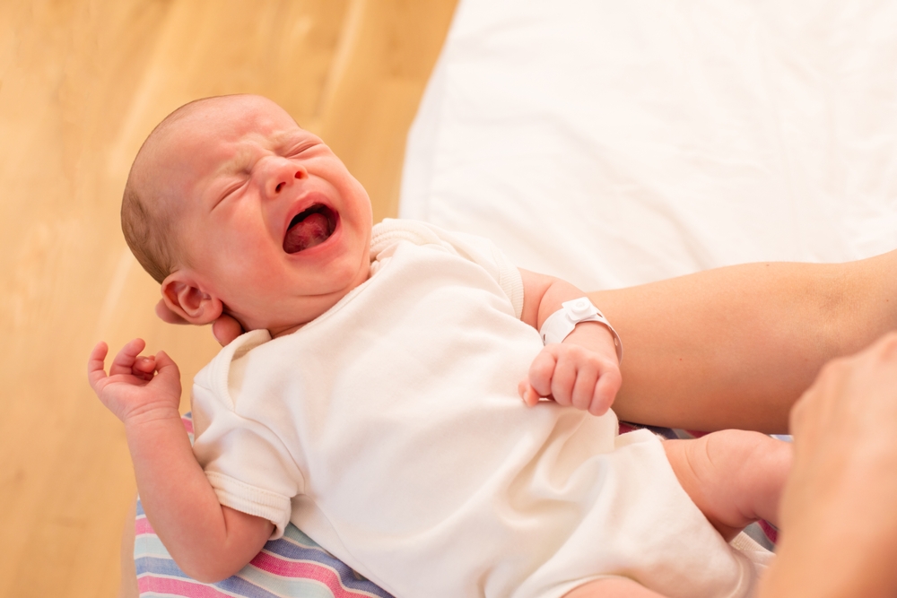 Un bebeluș care plânge și căruia i se vede frenul lingual