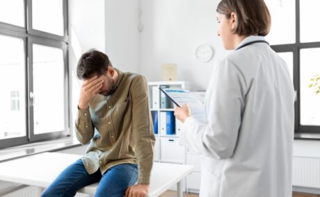 Un bărbat pe un pat, în cabinetul medicului, în timp ce discută despre infertilitatea la bărbați