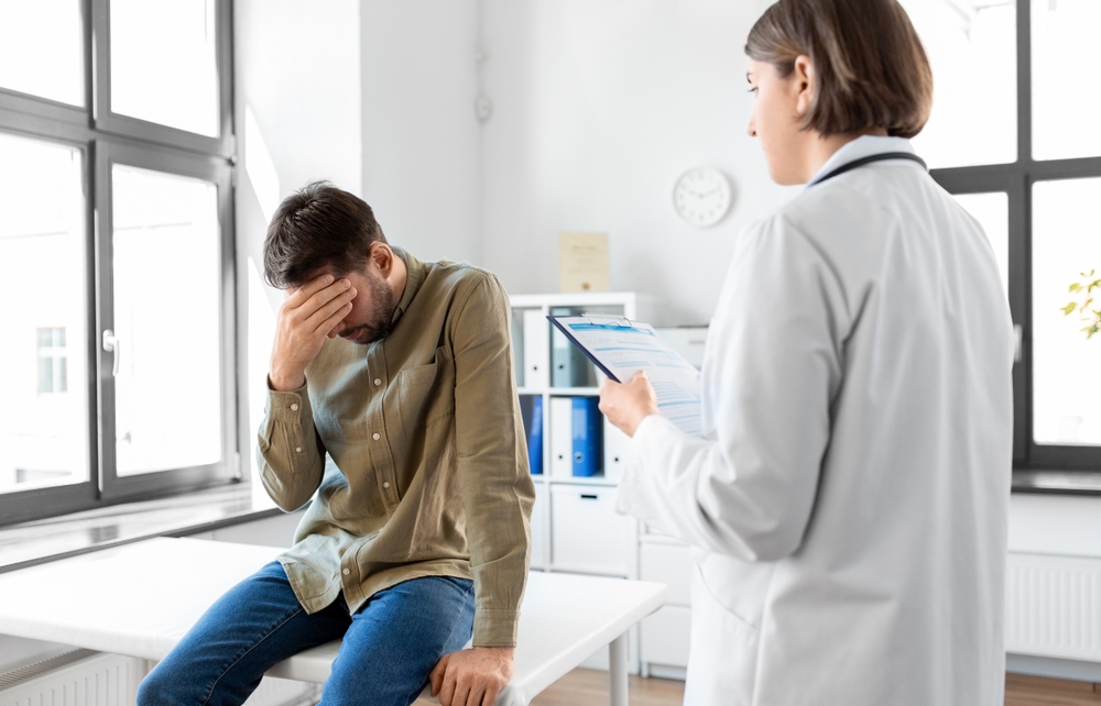 Un bărbat pe un pat, în cabinetul medicului, în timp ce discută despre infertilitatea la bărbați