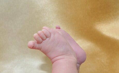 Picioare de bebeluș cu degete care au sindromul turnichetului, pe un fundal auriu