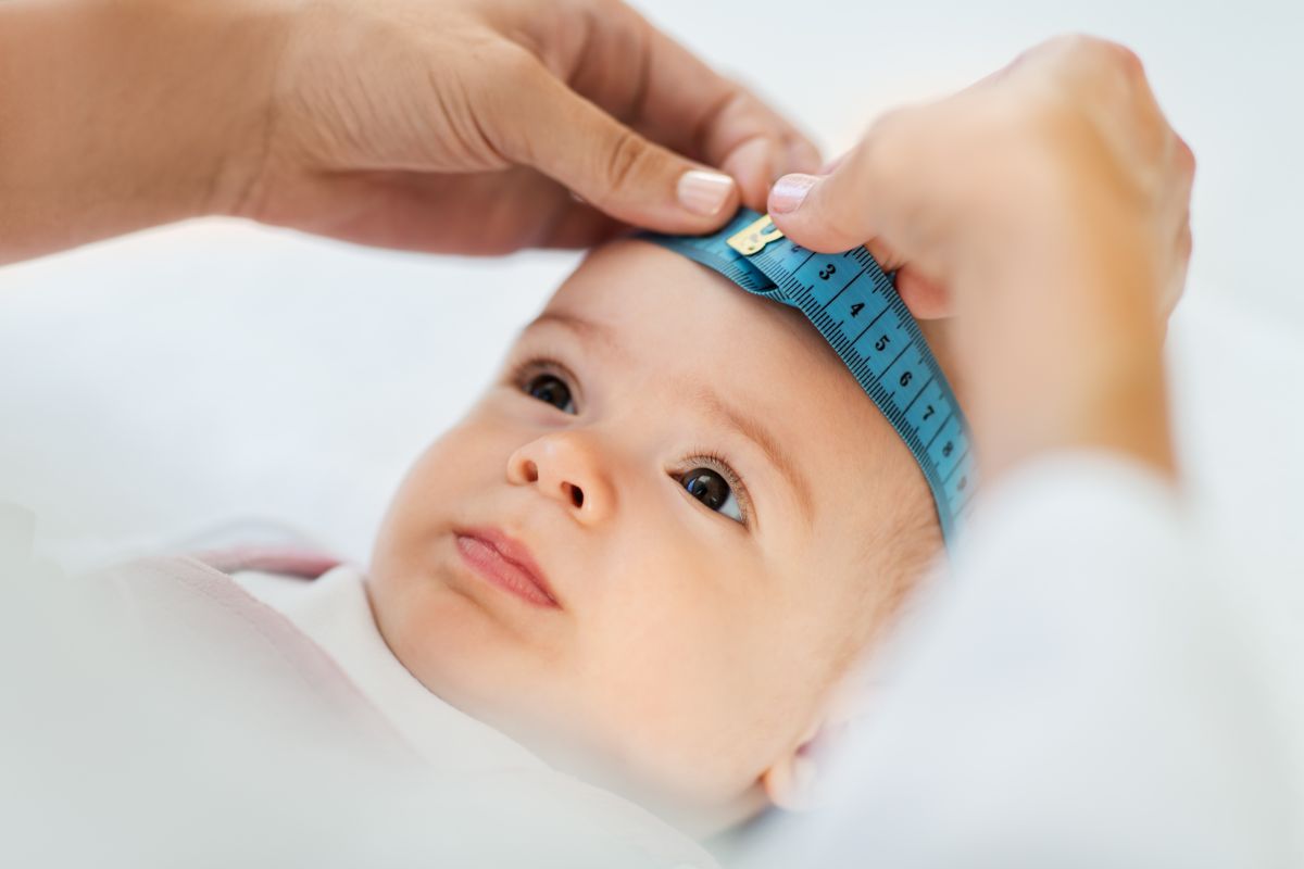 Capul unui bebeluș care este măsurat cu un centimetru albastru pentru a vedea dacă se confruntă cu hidrocefalia