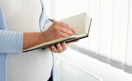 O femeie însărcinată care scrie într-un jurnal
