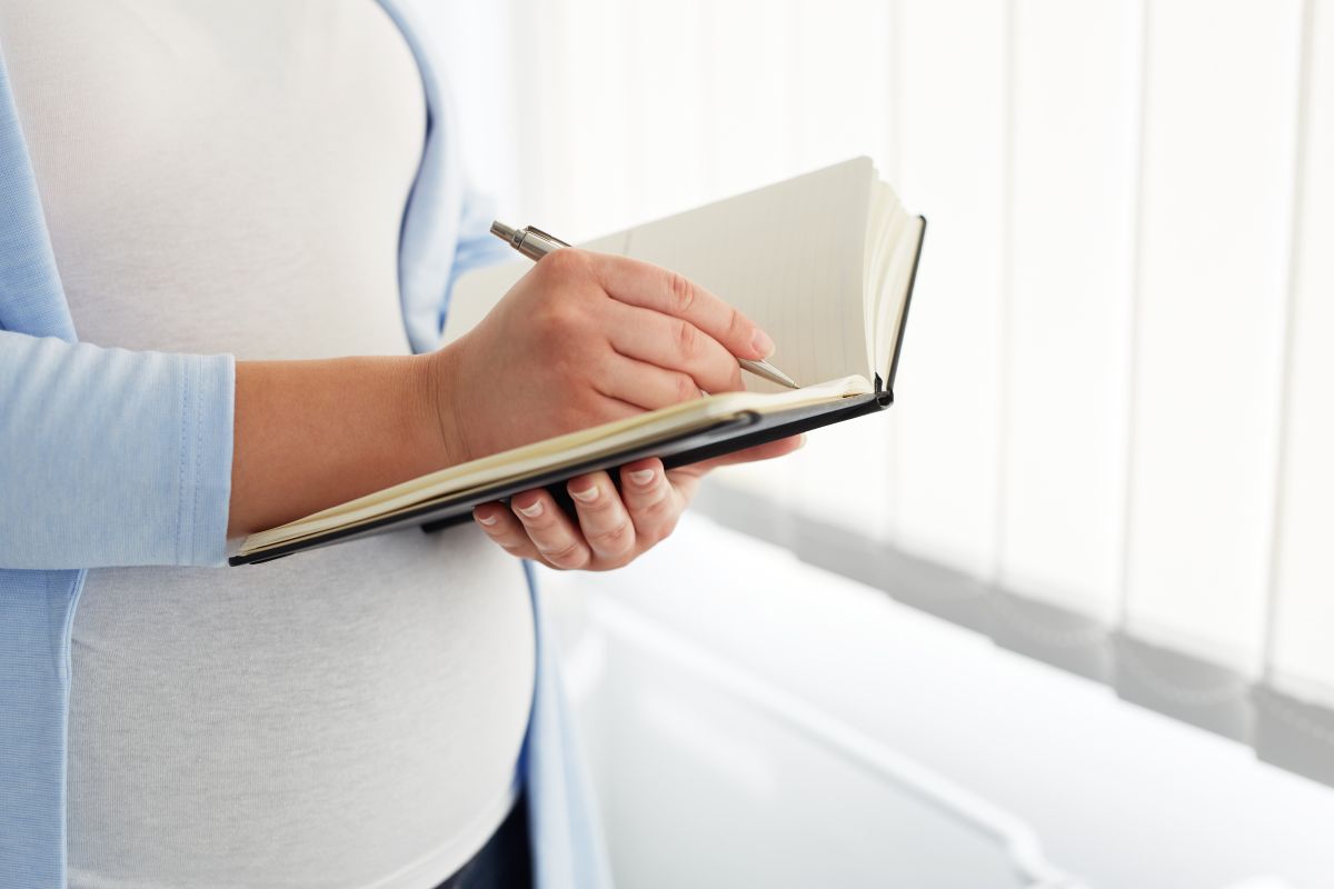 O femeie însărcinată care scrie într-un jurnal