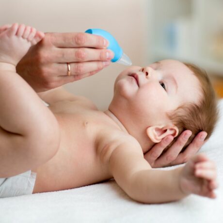 O mamică care curăță nasul bebelușului cu un aspirator nazal