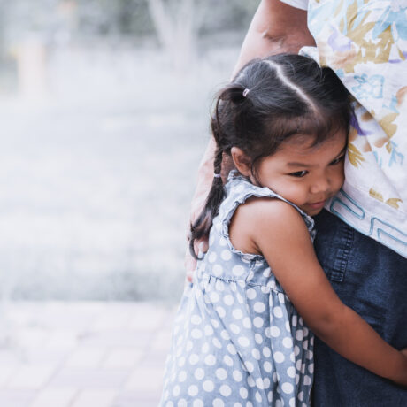 O poză cu o fetiță care îmbrățișează piciorul unui adult, folosită pentru a ilustra un articol despre cum să nu transmiți anxietatea ta copiilor