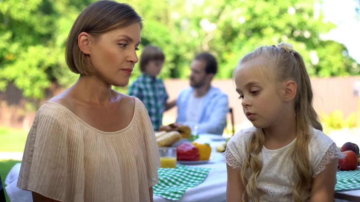 Mama, îmbrăcată cu o bluză bej care se uită spre fiica ei și stau cu spatele la o masă câmpenească, organizată în curte, und emai sunt și alți membrii ai familiei, iar pe fundal se vede și o pădure înverzită, ilustrând faptul că îți faci copilul de rușine
