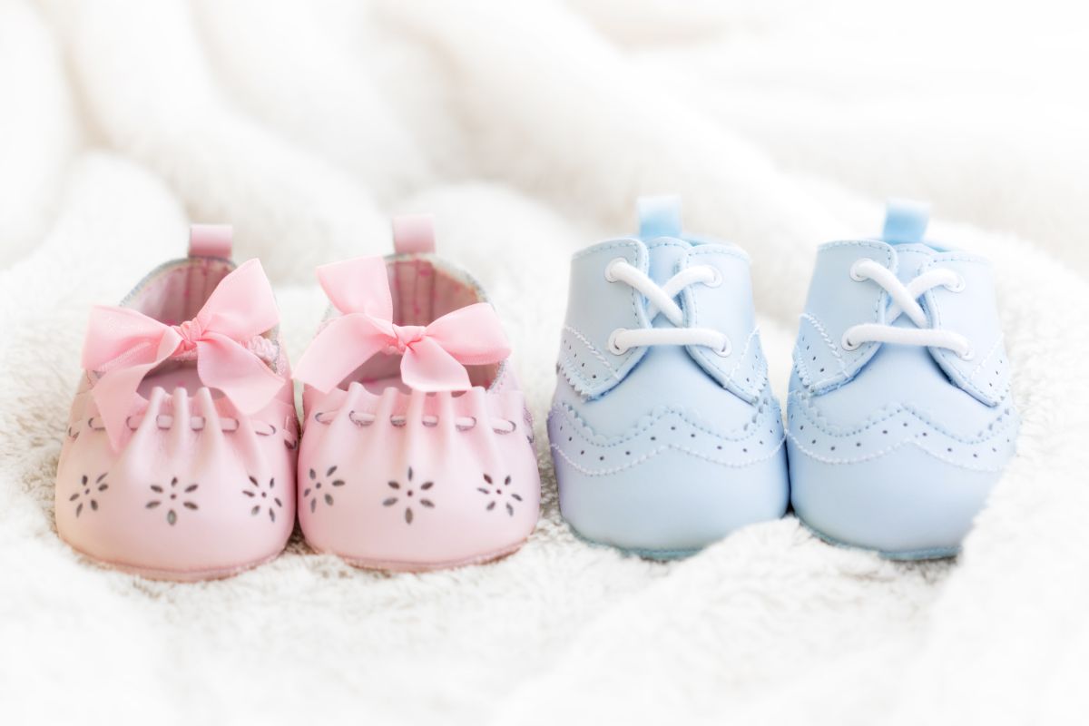 Botoșei roz și bleu, așezați pe o pătură albă, pufoasă, ilustrând Semne că poți avea fată sau băiat