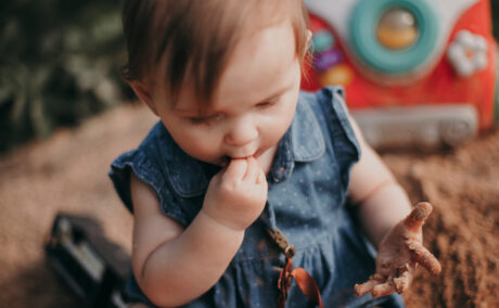 O fotografie cu un bebeluș care mănâncă nisip, utilizată pentru a ilustra sindromul Pica