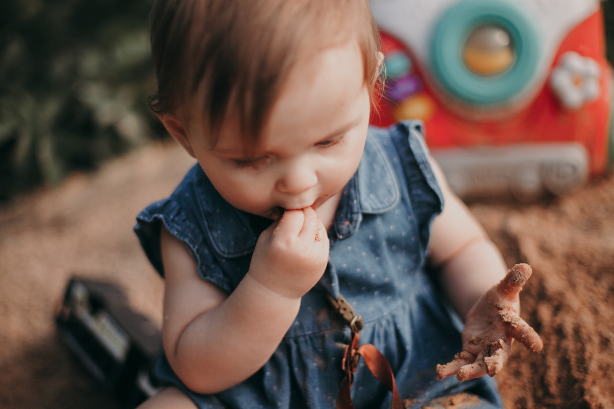 O fotografie cu un bebeluș care mănâncă nisip, utilizată pentru a ilustra sindromul Pica