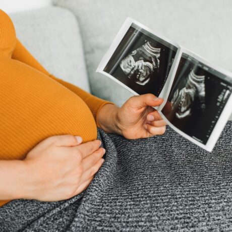 O femeie însărcinată în primul trimestru de sarcină, cu o ecografie a bebelușului în mână