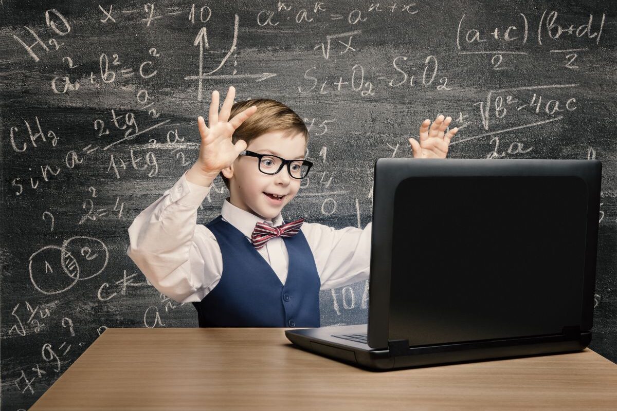 Băiețel cu ochelari de vedere, îmbrăcat cu cămașă albă, vestă bleumarin și papion cu dungi roșii, care stă la birou, cu mâinile ridicate, având în față un laptop, iar în spate are o tablă pe care sunt scrise formule matematice, ilustrând 5 probleme pe care le pot avea copiii supradotați