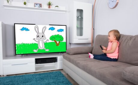 Bebelușul care se uită la televizor pe o canapea de culoare gri