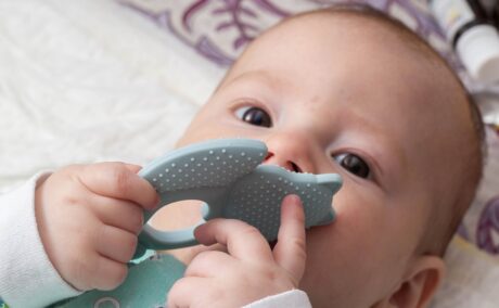 Bebeluș ține în gură o jucărie pentru dentiție