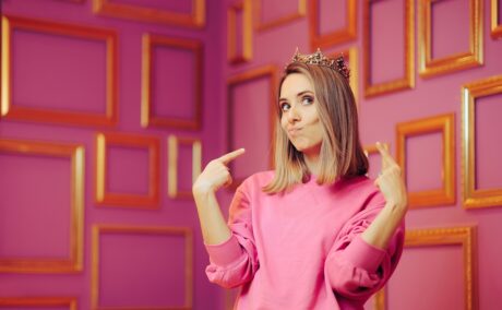 Femeie narcisistă, fotografiată pe un fundal roz, cu o coroană pe cap