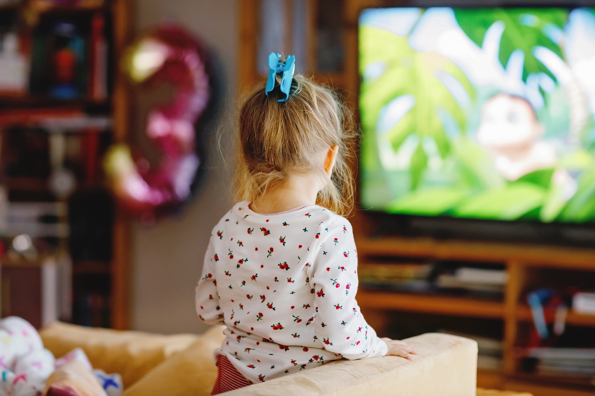 O fetită blondă, care se uită la televizor
