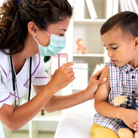 Medicul îi face unui băiat vaccinul antigripal în cabinet