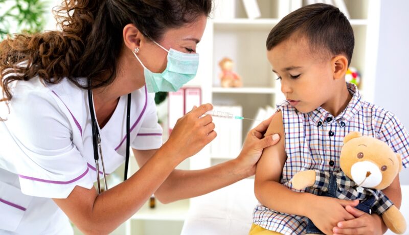 Medicul îi face unui băiat vaccinul antigripal în cabinet
