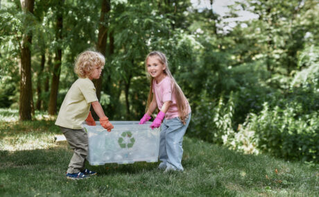 Doi copii care strâng gunoaie în pădure