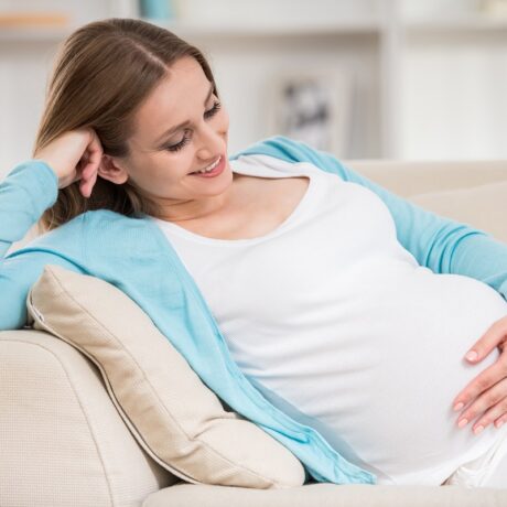 Femeie însărcinată se relaxează pe canapea