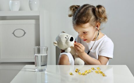 Fetița care se joacă de-a doctorița cu ursulețul de pluș și îi dă suplimente alimentare