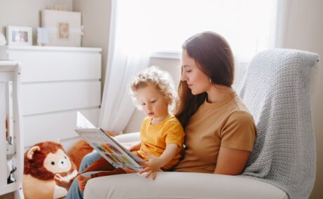 Mama își ține copilul în brațe și-i citește o poveste despre inteligența emoțională la copii