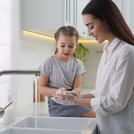 Mama și fetița se spală pe mâini la chiuveta din bucătărie