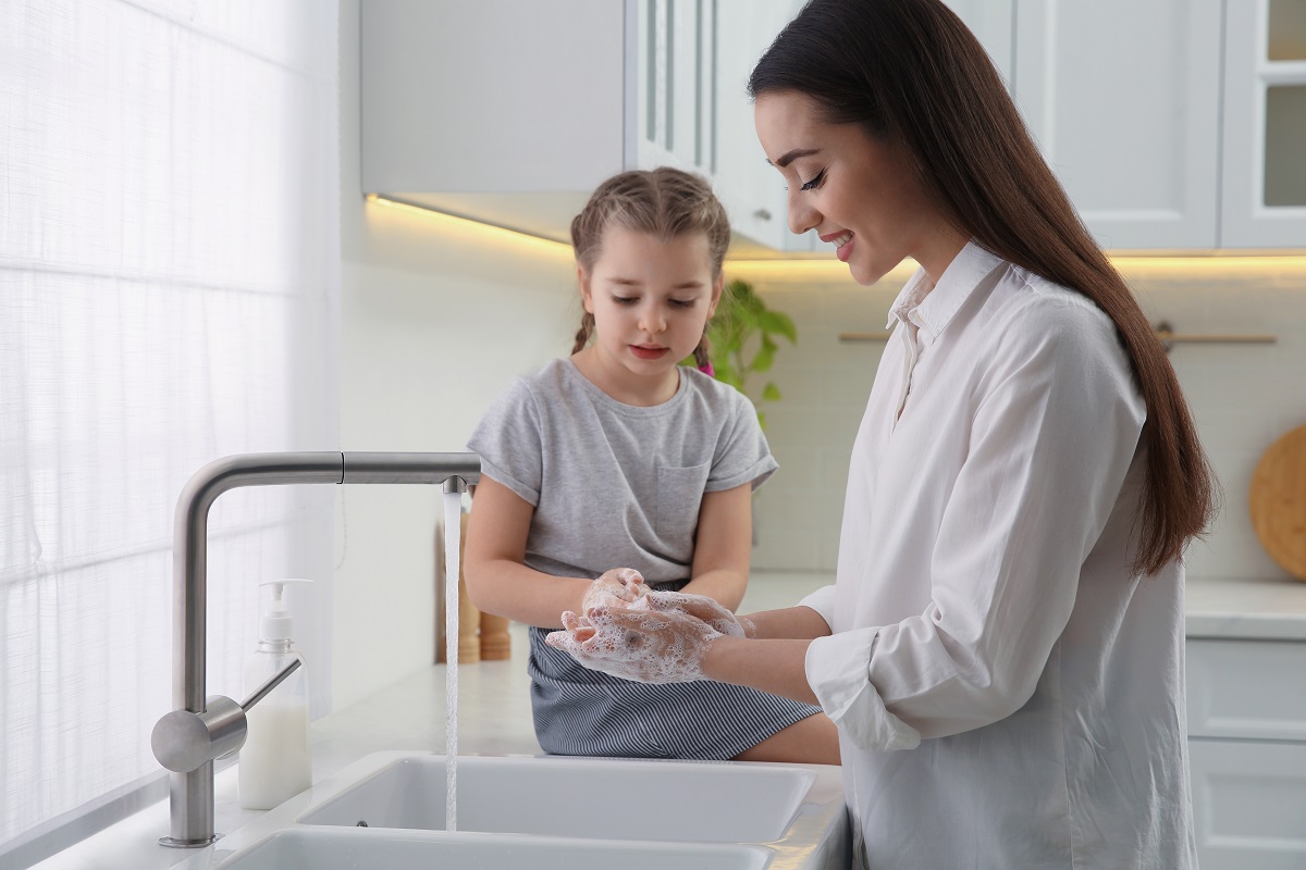 Mama și fetița se spală pe mâini la chiuveta din bucătărie