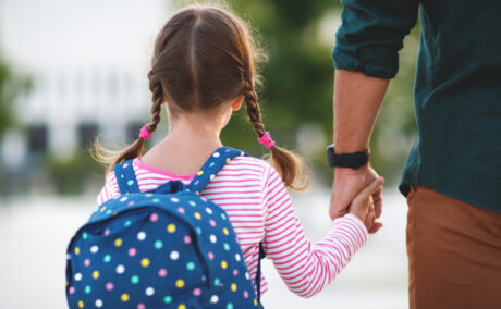 O fetiță care merge la școală de mână cu tatăl ei