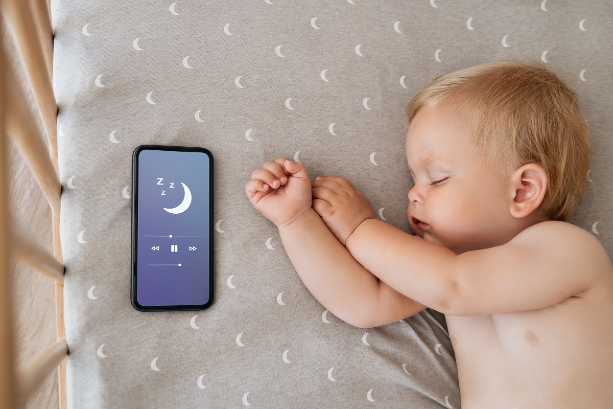 Bebelușul doarme cu un dispozitv de sunet lângă el