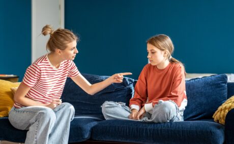 Mama își cearta fetița care stă pe canapea