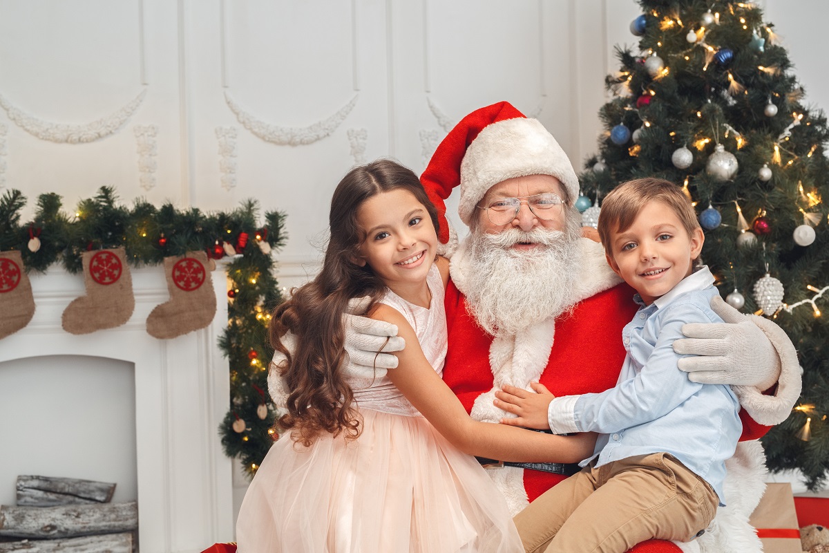 Moș Crăciun ține în brațe o fetiță și un băiețel