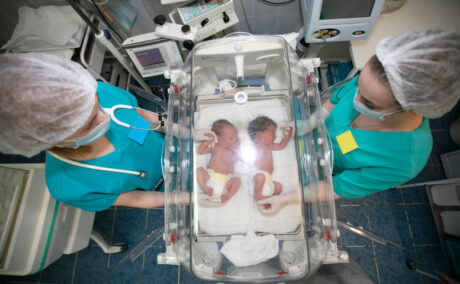 Două asistente lângă un incubator cu gemeni
