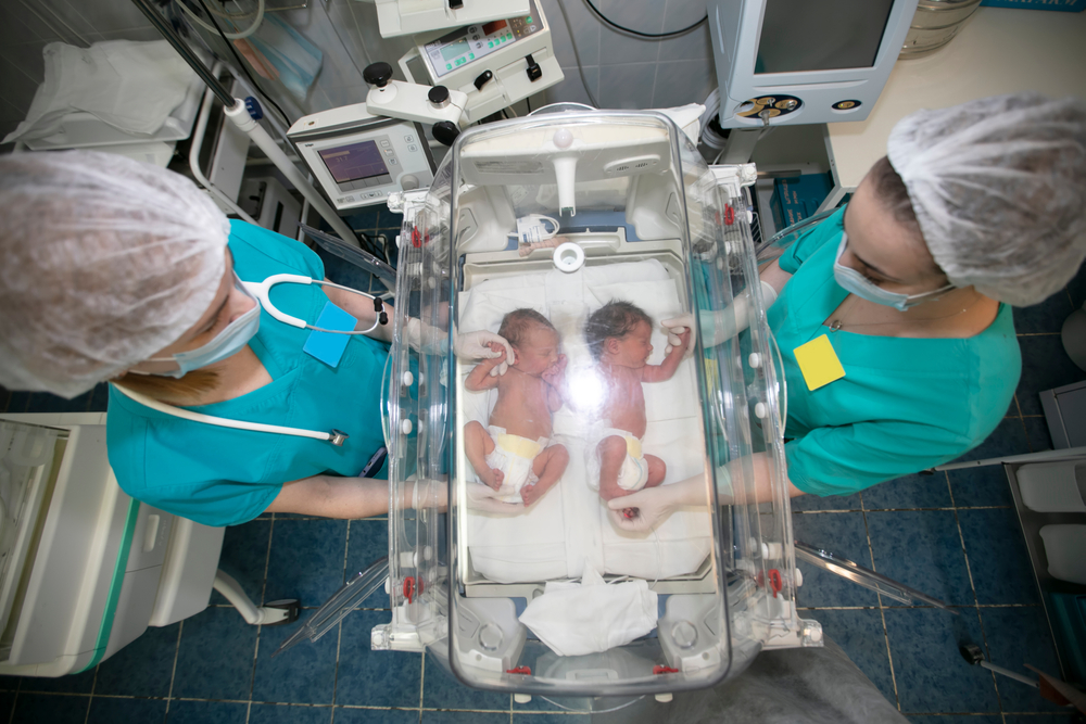 Două asistente lângă un incubator cu gemeni