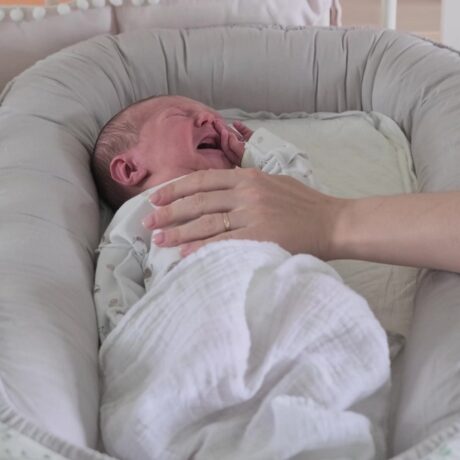 Bebeluș plânge în timp ce doarme, iar mâna mamei îl liniștește