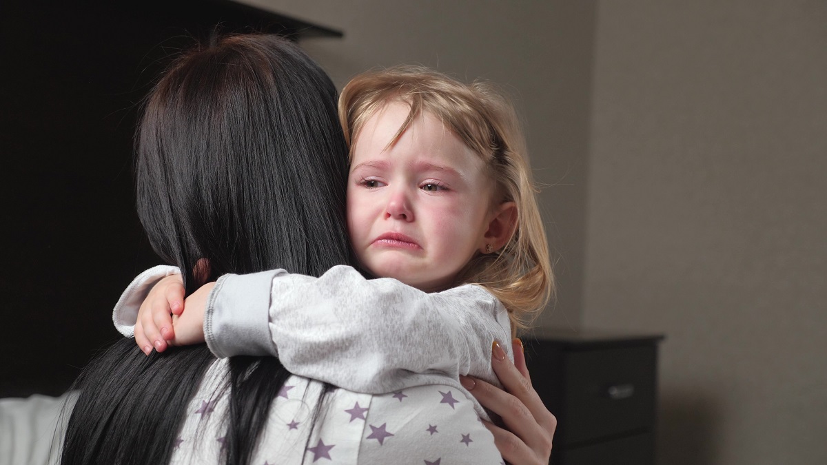 Fetiță plânge în timp ce mama o îmbrățișează