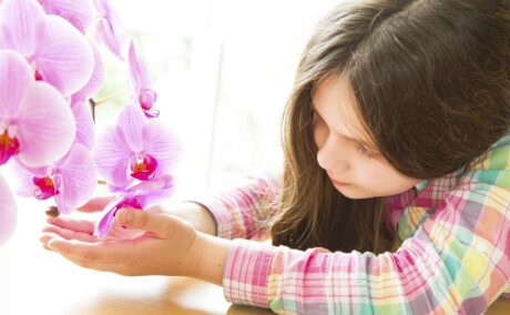 Fetiță care se uită la o orhidee