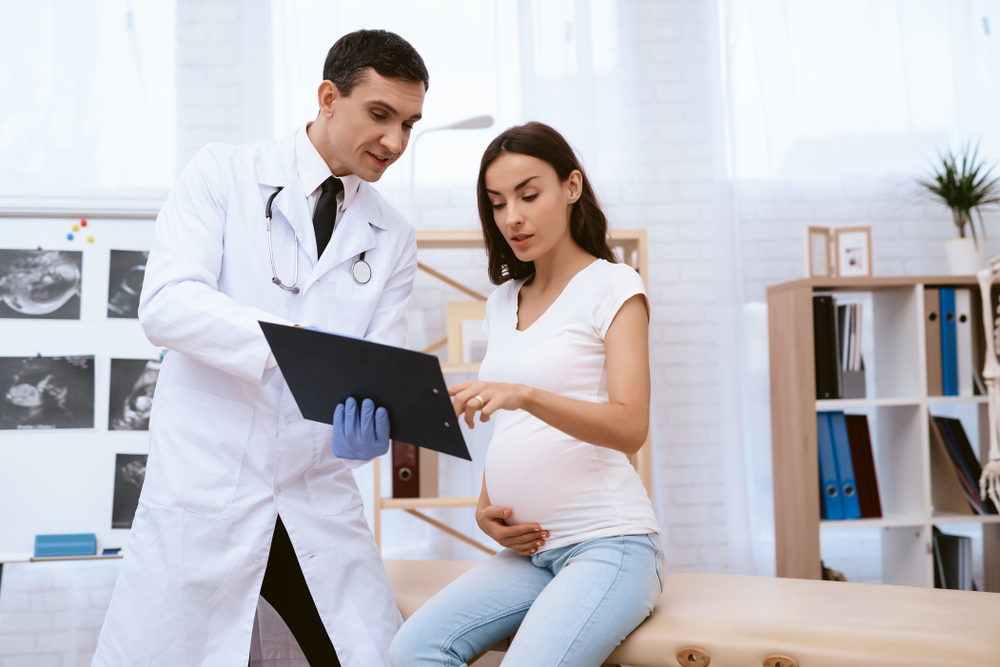 Femeie gravidă în cabinetul doctorului stă de vorbă cu el