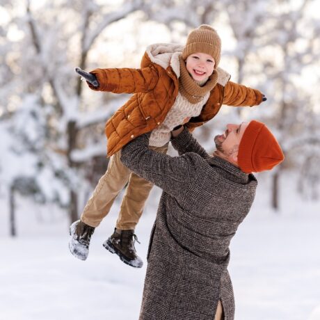 Tata se joacă cu copilul în zăpadă