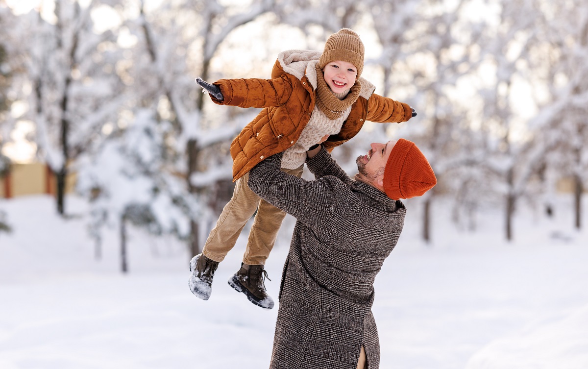 Tata se joacă cu copilul în zăpadă