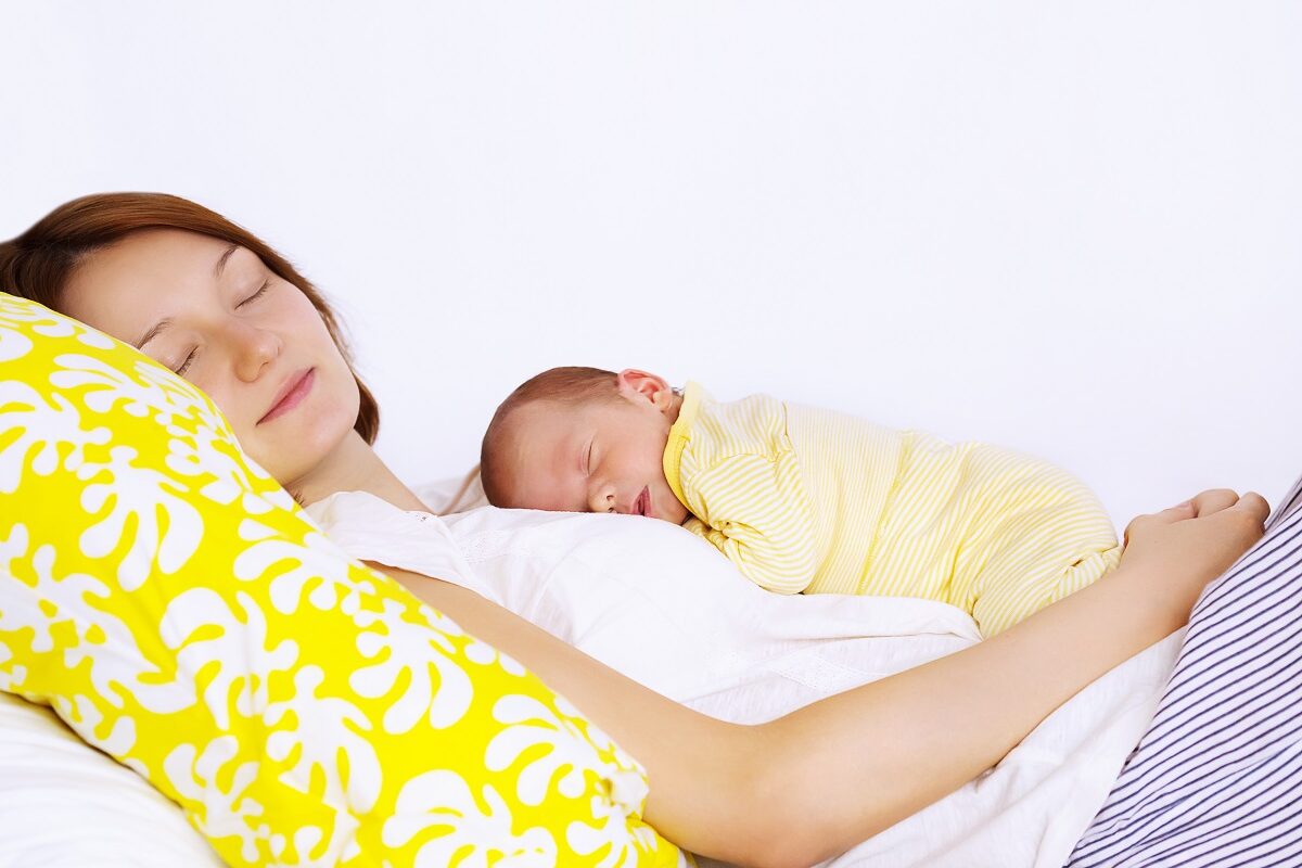 Mama doarme cu bebelușul în brațe