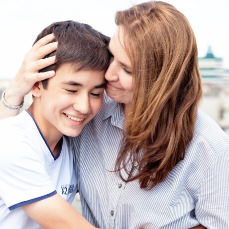 Mama își îmbrățișează băiatul adolescent