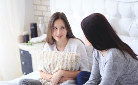 Mama și adolescenta stau pe canapea și discută