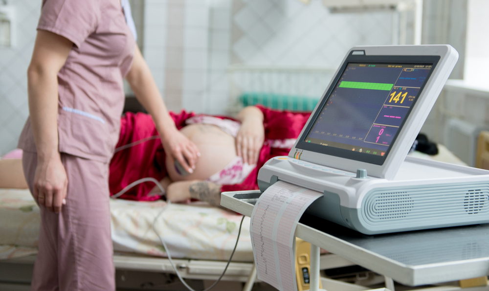 Femeie însărcinată pe patul de spital, la un consult ginecologic