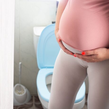 O femeie gravidă care stă aproape de toaletă