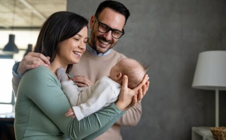 Portret de familie cu mamă, tată și bebeluș care este ținut în brațe