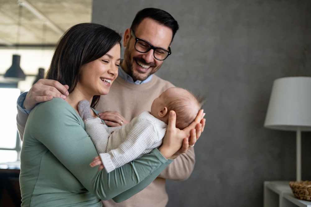 Portret de familie cu mamă, tată și bebeluș care este ținut în brațe