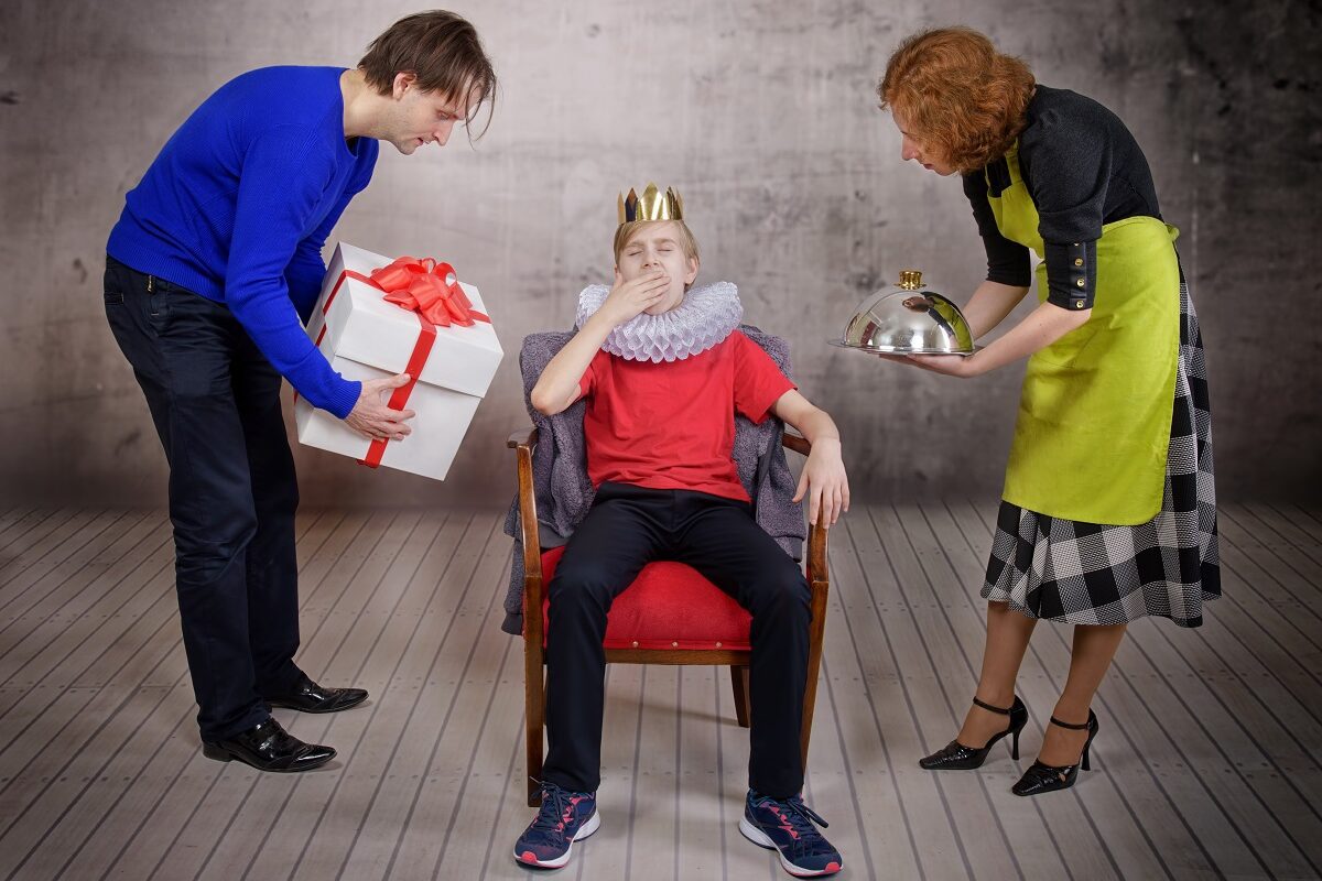 Mama și tata îi aduc daruri copilului care stă pe un scaun ca un rege