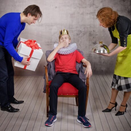 Mama și tata îi aduc daruri copilului care stă pe un scaun ca un rege